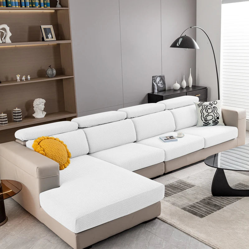 A modern beige sofa with white cushions and a gray rug in a living room setting.