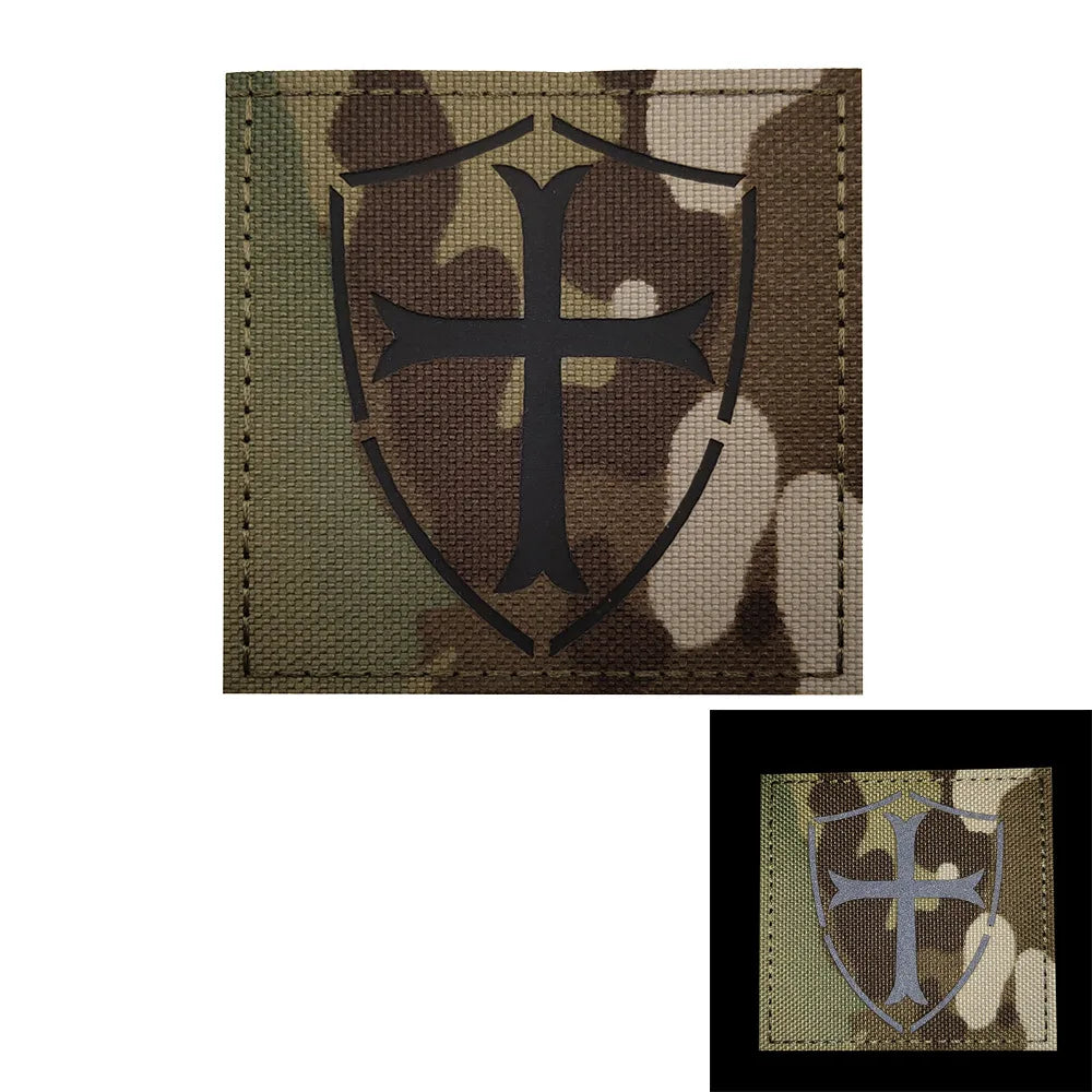 Olive drab camouflage patch featuring a black cross design on a shield shape