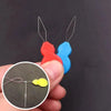 A hand holds a plastic threader set with red and blue components, showing the separate threader pieces.
