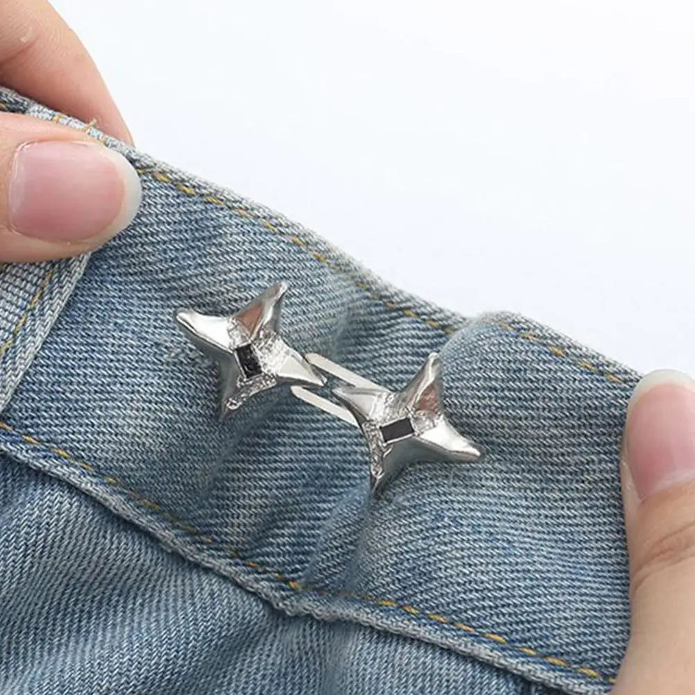 A close-up of a silver star-shaped adjustable waist tightening buckle attached to denim fabric.