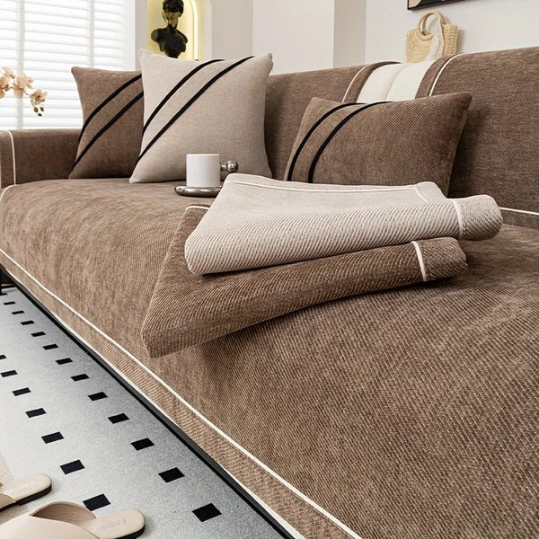 A luxurious brown chenille sofa protector cover with striped pillows and a matching floor accent.