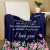 A dark blue throw blanket with pink floral embroidery is draped over a chair.
