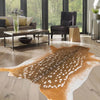 A large, irregular brown and white faux animal skin rug placed on a light wood floor in a modern living room.