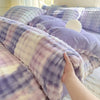A purple and white plaid fleece duvet cover with a white pillow on a bed.