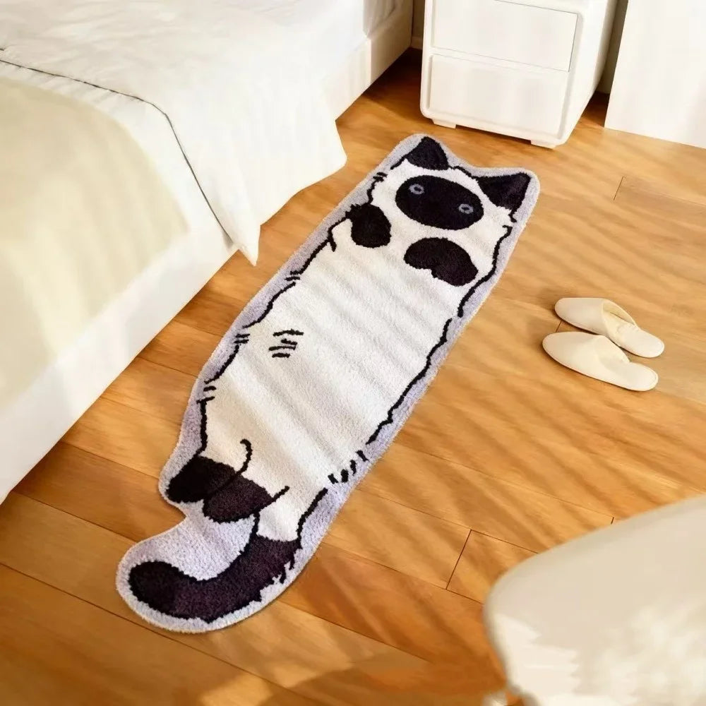A long, rectangular plush rug featuring a black and white cartoon cat design placed on a wooden floor next to a bed.