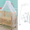 A wooden infant cot with a sheer white mosquito net canopy draped over it.