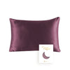 A deep plum colored silk pillowcase with a hidden zipper and a crescent moon design on the tag.