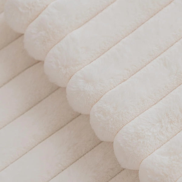 Close-up of a beige square faux rabbit fur cushion cover with quilted lines.
