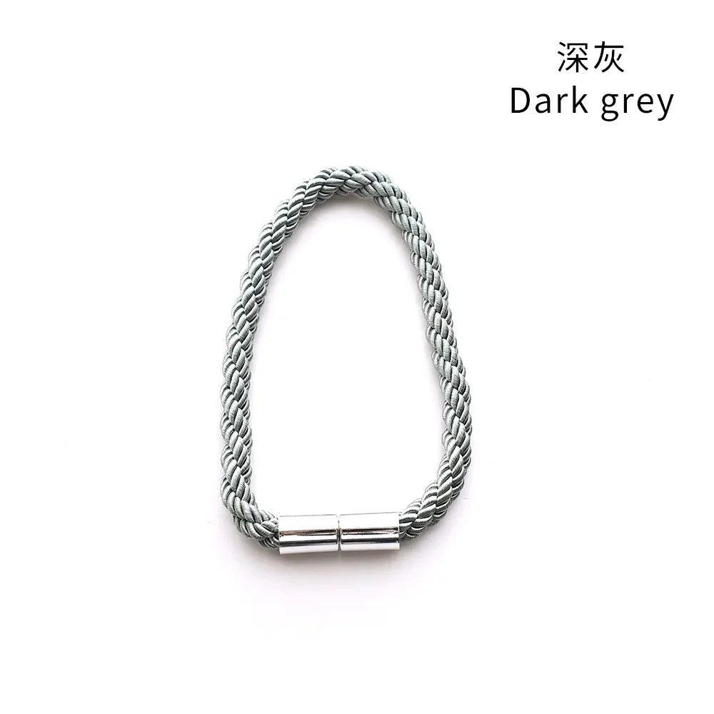 A close-up of a dark grey magnetic curtain tieback clip.