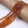 A strand of faceted amber glass beads is draped over a cylindrical object.