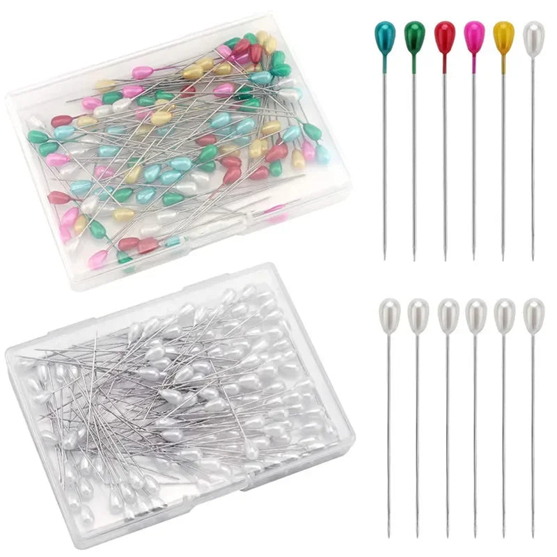 A collection of pearl teardrop corsage boutonniere pins in various colors and finishes, displayed in clear plastic containers