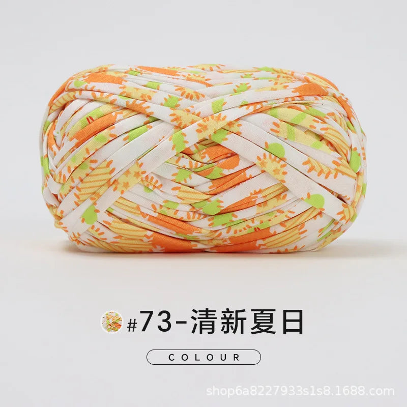 A ball of hand-dyed fabric strip yarn featuring an orange and white pattern for crochet and knitting.