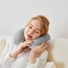 A woman rests her head on a gray bamboo fiber U-shaped travel neck pillow while relaxing.