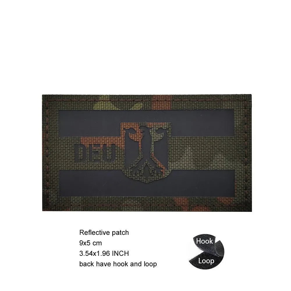 A dark rectangular reflective patch featuring an eagle shield design on a camouflage background.