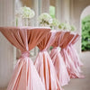 Pink satin table overlay cloths draped in a vertical line with white floral arrangements in a bright indoor setting.