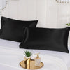 Black satin pillowcase set displayed on a white bed with gold decorative accents.