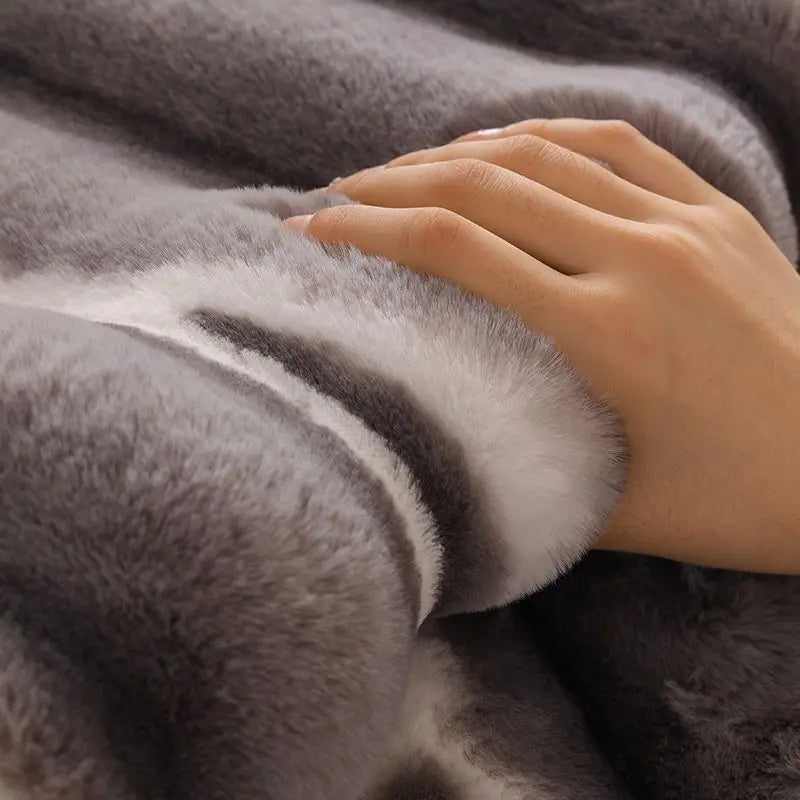 A hand gently touches a gray and white plush velvet sofa protector cover.