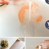 A hand is pouring water onto a white reusable EVA drawer liner, causing an orange stain to form.