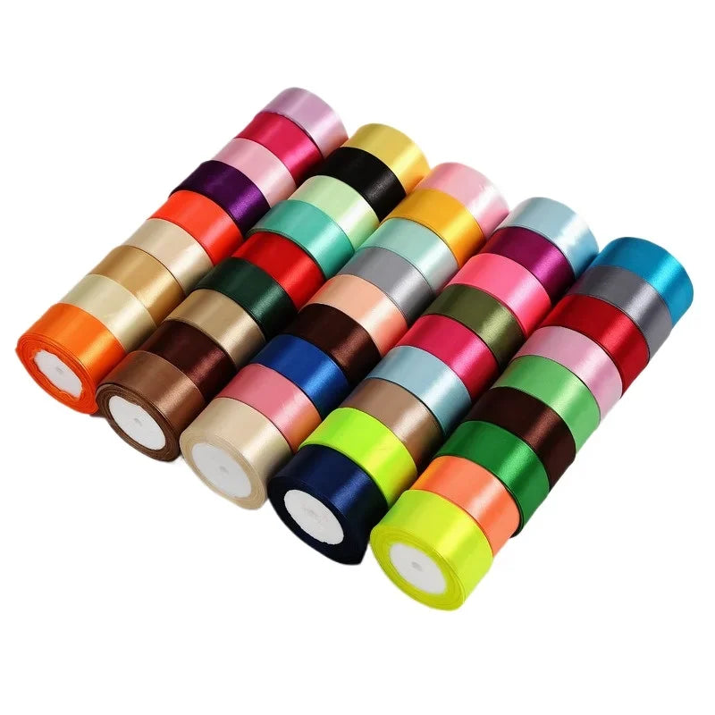 A collection of satin craft ribbons in various colors, arranged in a diagonal line.