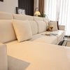 A beige stretch sofa seat cushion cover displayed on a light-colored sofa with decorative pillows and natural light.