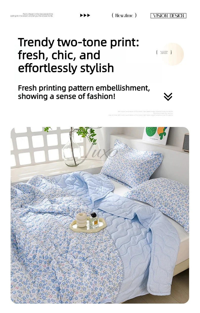 A light blue floral patterned quilt set featuring a two-tone print with white and blue tones.