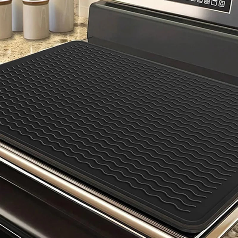 A black heat-resistant silicone stove top cover mat is shown inside a cooking appliance.