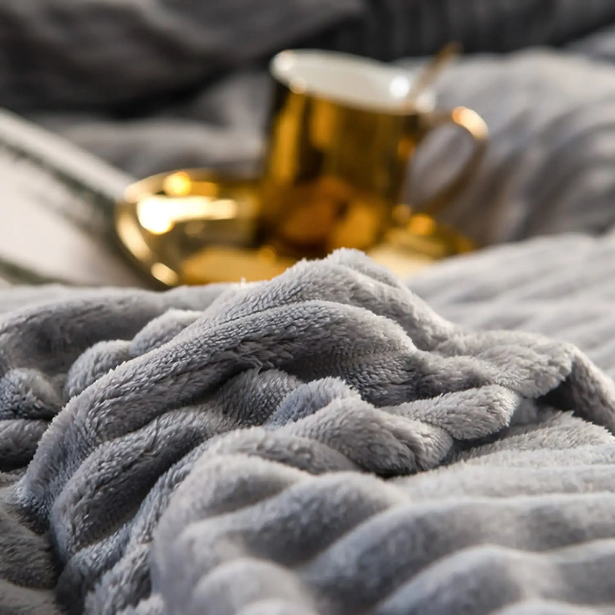 A close-up of a soft gray corduroy duvet cover set with a gold mug resting on the fabric.