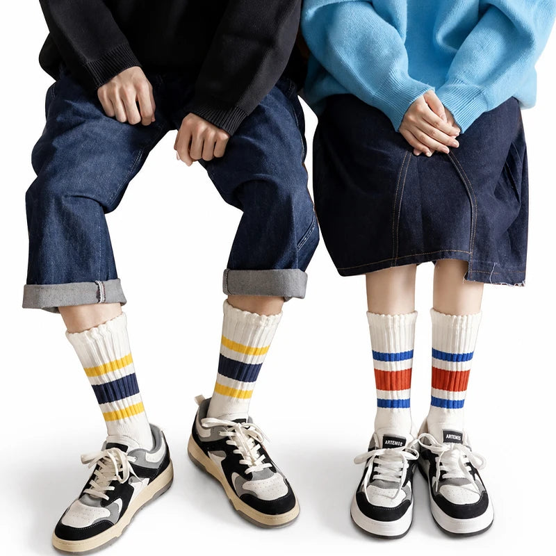 A pair of men's retro striped crew socks worn by a person, paired with dark denim jeans and a navy blue sweater.