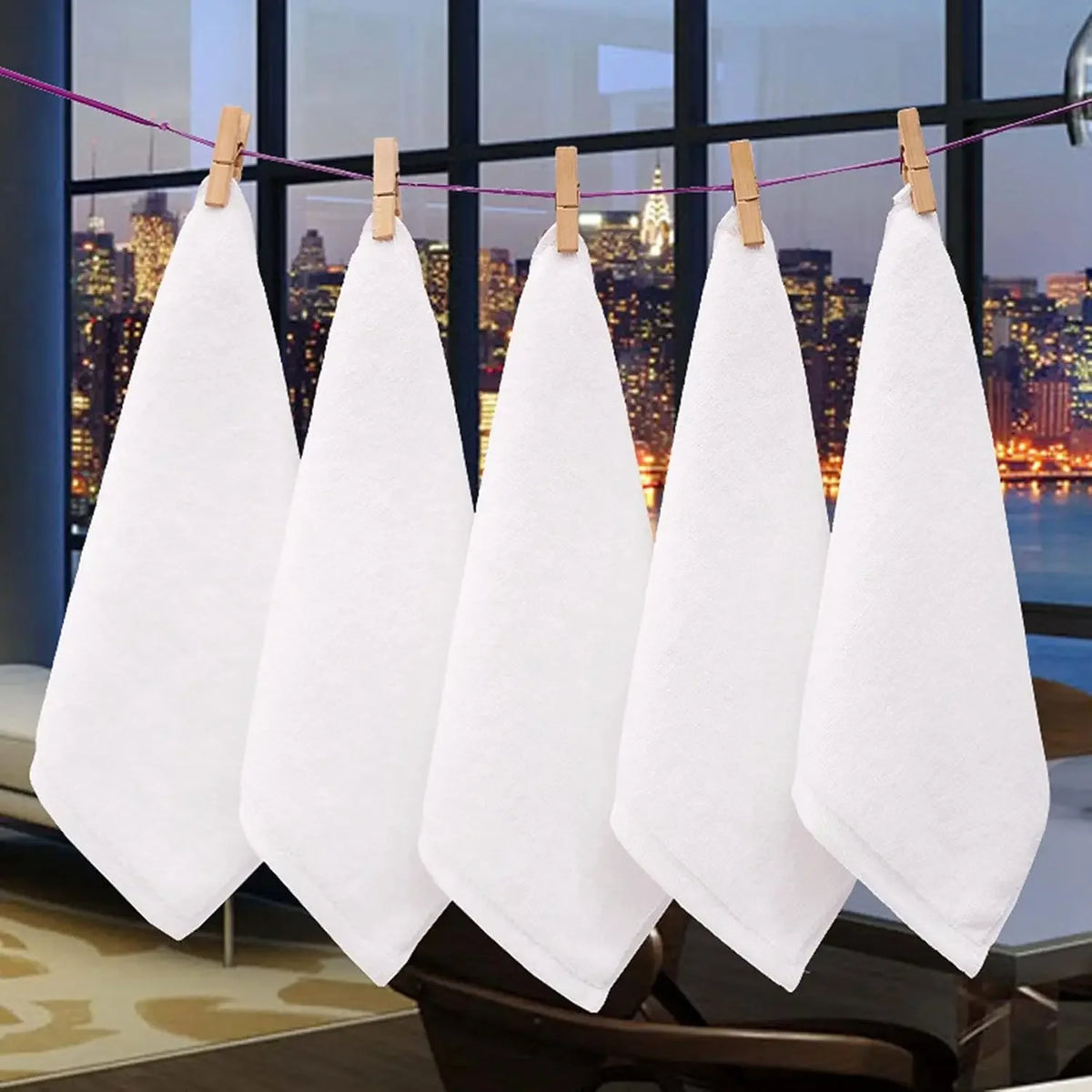 A set of ten white cotton face towels are hanging on a clothesline in a modern interior setting.