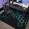 A black hexagonal gaming area rug with glowing cyan neon lines is placed on a desk setup.