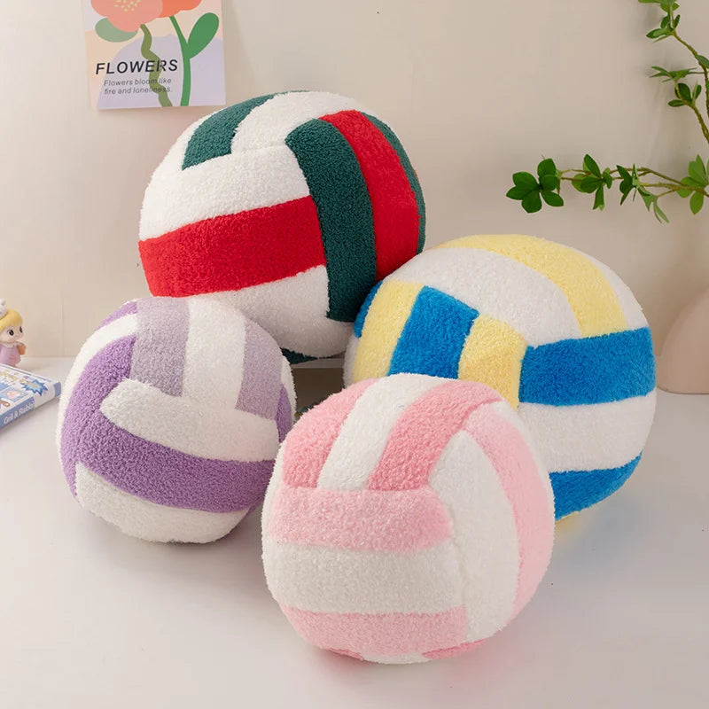 A collection of colorful plush volleyball balls in various stripes and solid colors resting on a white surface.