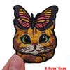 An embroidered patch of a cartoon cat face with pink and yellow wings.
