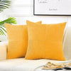 A set of yellow corduroy patchwork pillow covers displayed on a light-colored sofa.