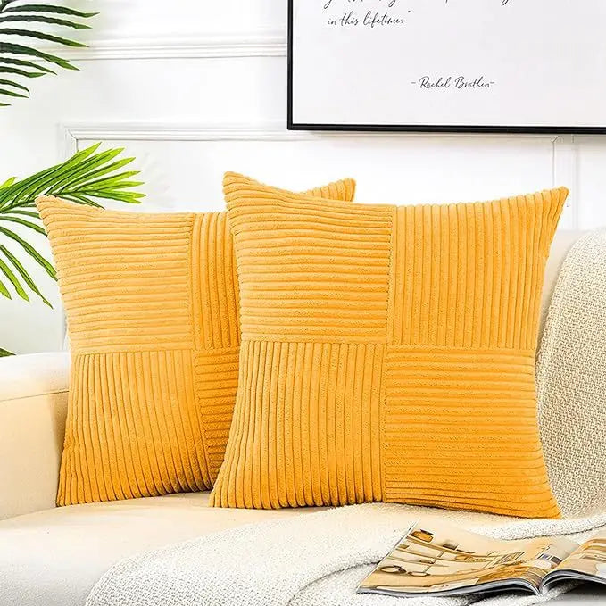 A set of yellow corduroy patchwork pillow covers displayed on a light-colored sofa.