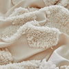 A close-up of a cream textured fabric, likely a duvet cover set, draped and folded.