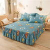 A teal printed bed skirt with yellow and orange floral patterns is displayed on a bed.