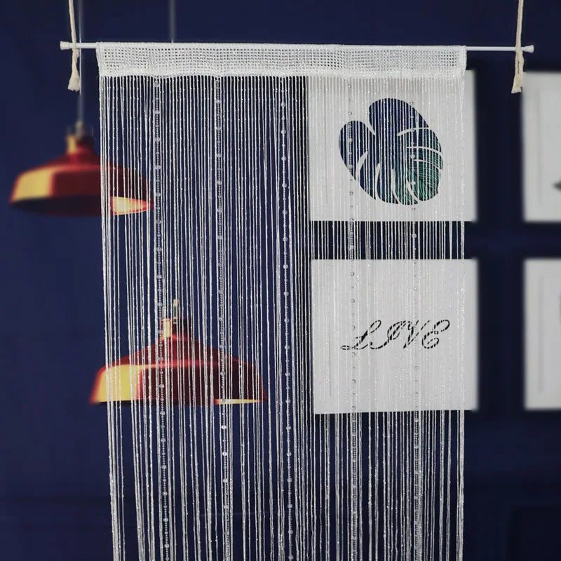 White beaded string curtains hanging against a dark blue background with a heart design and text.
