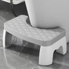 A white adjustable adult toilet squat stool with a padded seat and supportive legs is shown on a glossy floor.