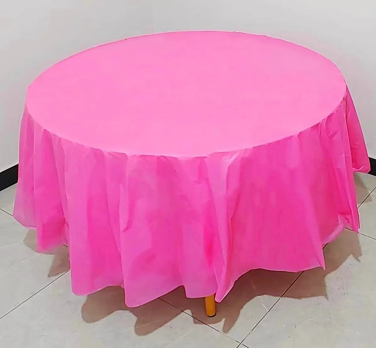 A round plastic disposable table cover in bright pink fabric displayed on a stand.