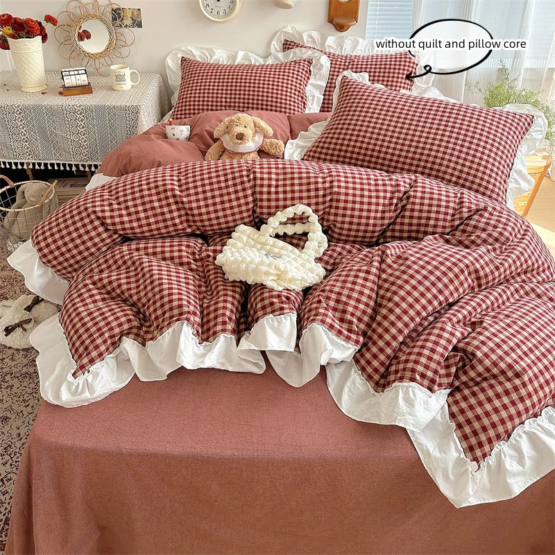 A plaid duvet cover set in red and white checks with lace embroidery displayed on a bed.