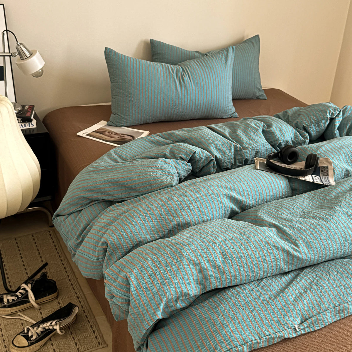A teal striped duvet cover set with matching pillows on a bed.