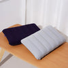 A navy blue and light gray portable inflatable travel pillow resting on a wooden surface.