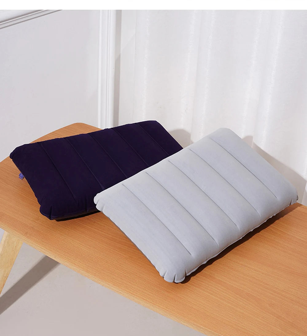 A navy blue and light gray portable inflatable travel pillow resting on a wooden surface.