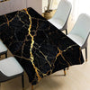 Black marble pattern table cloth with gold veining displayed on a dining table.