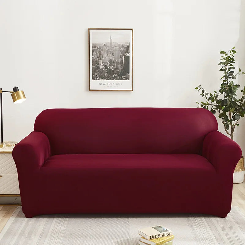 A deep burgundy universal stretch sofa with a modern design placed in a bright room.