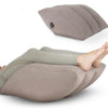 A beige inflatable leg elevation pillow shown in a storage bag, positioned under a person's foot.