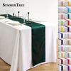 Elegant satin green table runner set for a formal dining table with white linens and glassware.