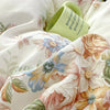 A close-up of floral cotton pillow covers in cream and pale green, showing a rolled tag with 'good morning' text.