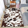 A brown and white faux cowhide pattern area rug placed on a wooden floor.
