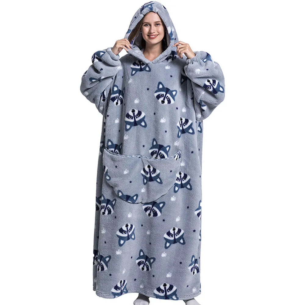A woman wearing a gray sherpa fleece oversized blanket hoodie with a hood and patterned design.